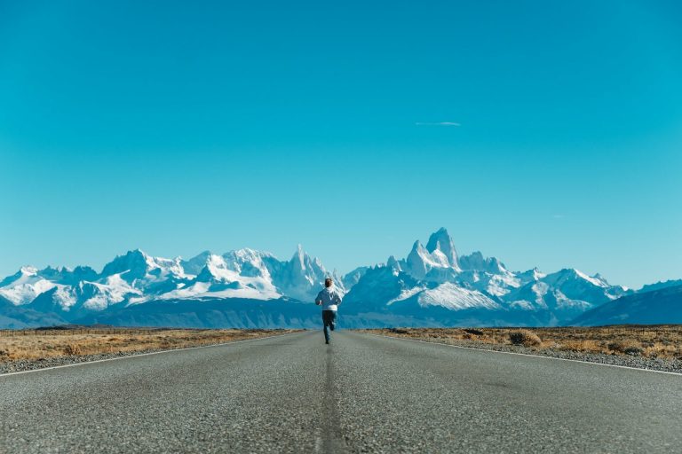 Runner in stunning landscape of snowy mountains and clear blue sky