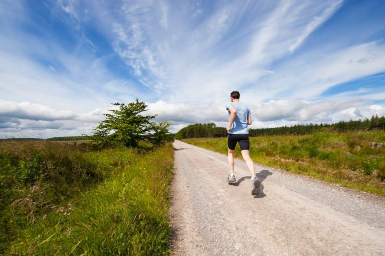 Man running down a dirt track through fields