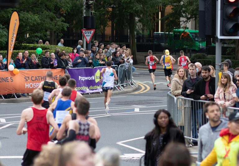 runners in club vests running the london marathon with crowd support