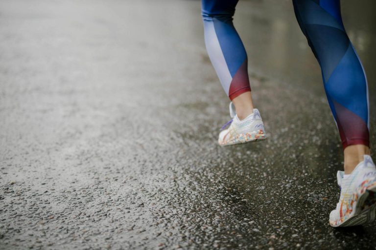 Runner striding through rain water on concrete
