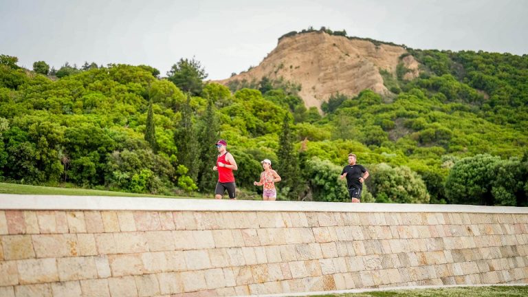 Parkrun tourists running against a stunning cliff landscape
