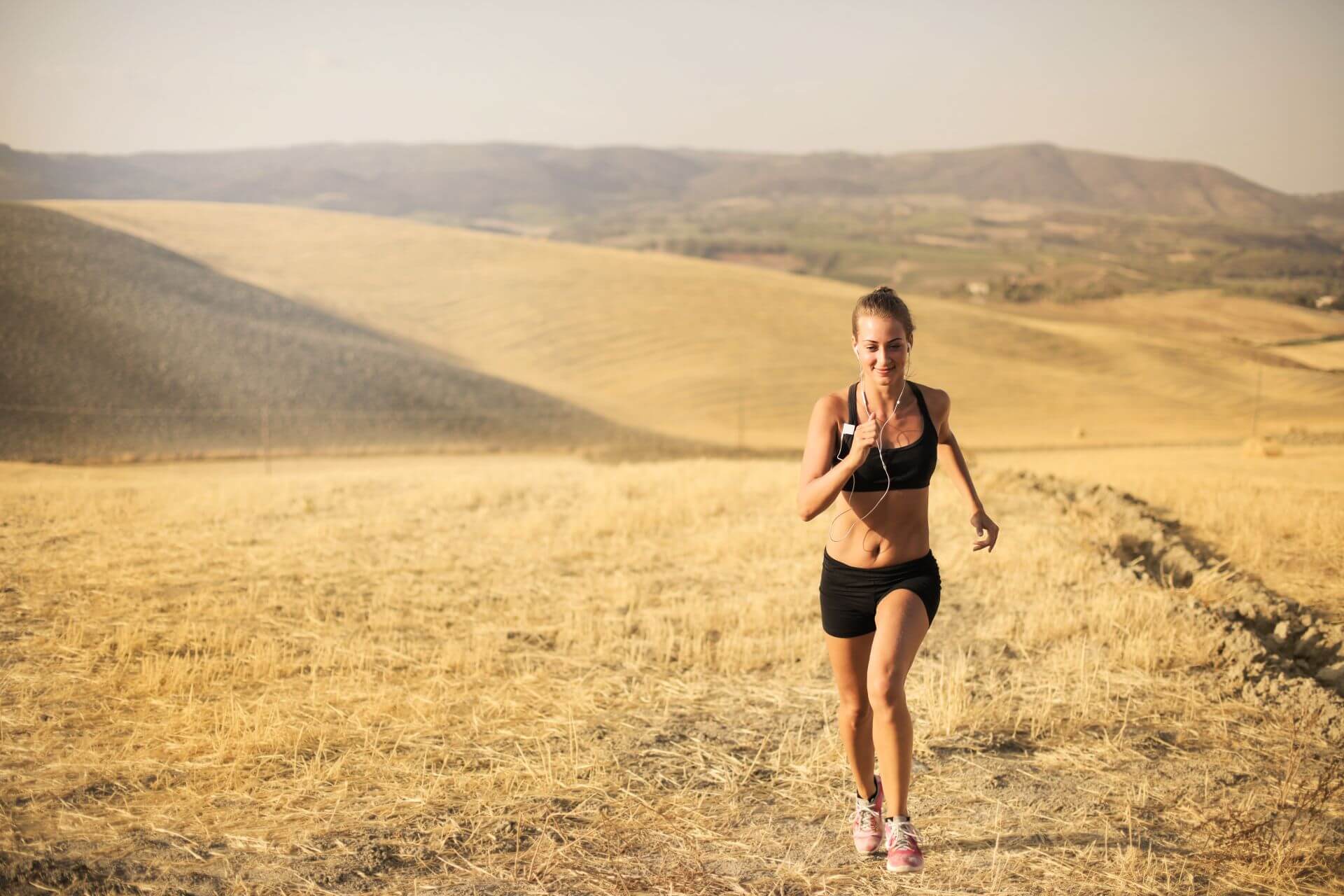 A runner running through a hot and dried out field during a heatwave in the UK