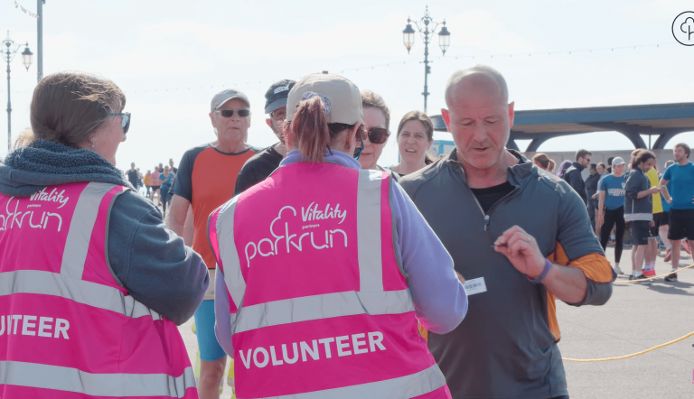 two marshalls handing out finish tokens while volunteering at parkrun