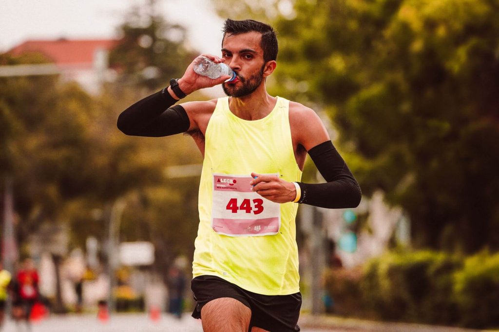 runner drinking water mid-run while running in a heatwave uk