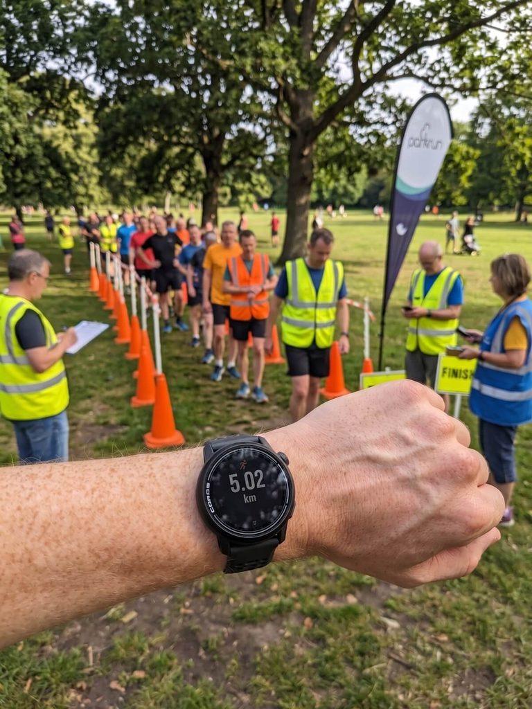 runner checking their good parkrun time on a GPS watch at the finish funnel